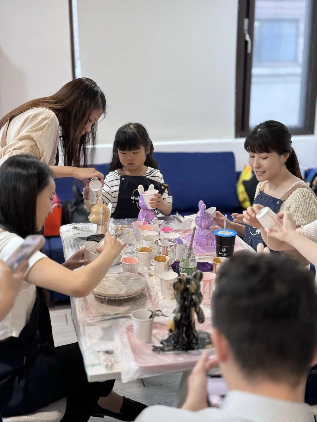 小朋友在 Made Studio 桌邊倒顏料製作流體熊，家長在旁協助｜台北兒童手作 DIY
